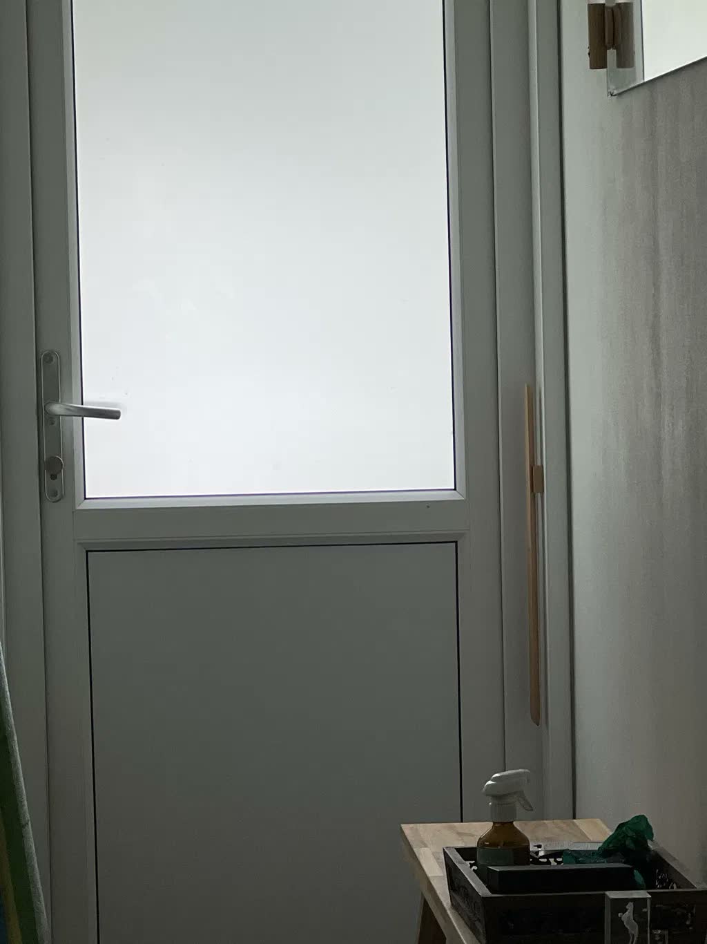 Kenkälusikka harmaalla seinällä takaovella, vieressä puutarhakenkiä
