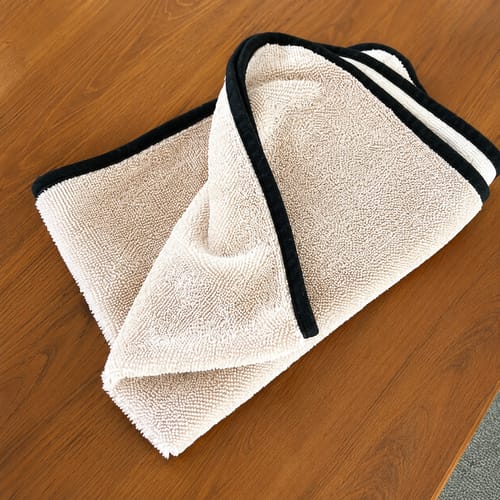 Beige Wove-mikrokuituliina taitettuna puiselle tasolle